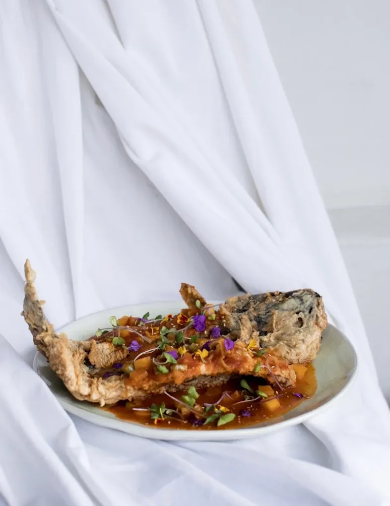 El mismo pescado crujiente emplatado sobre un mantel blanco